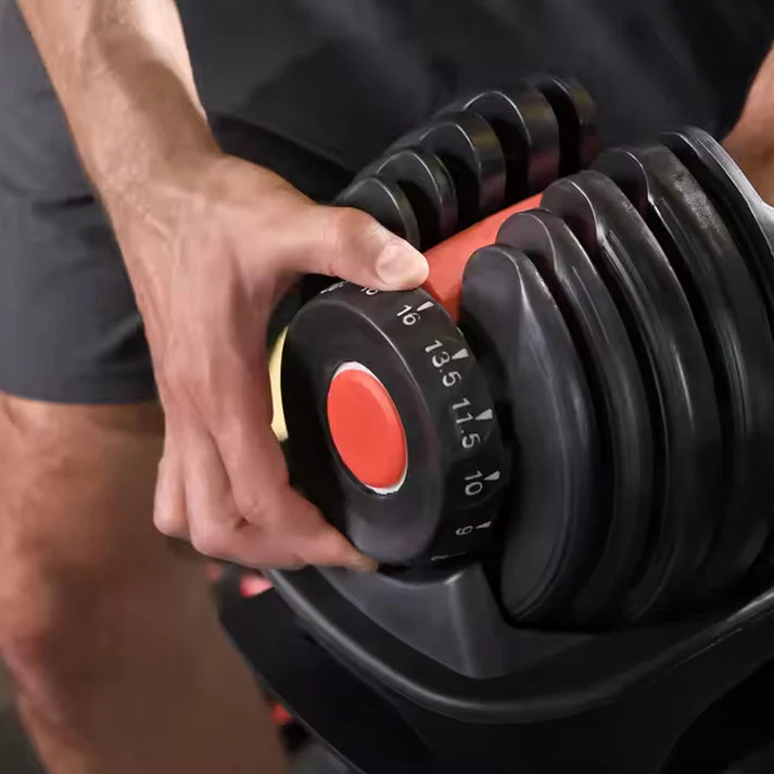 Person adjusting a black adjustable dumbbell with red markings.